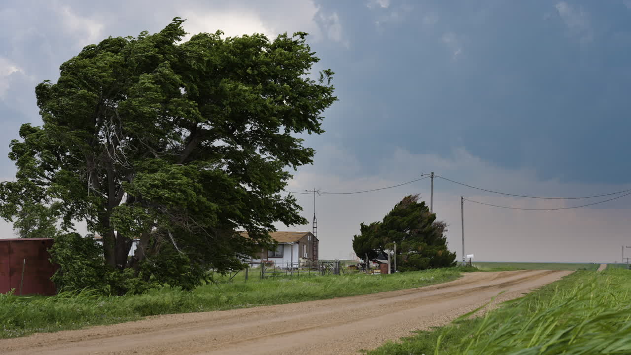 Stormy Sky And Strong Winds Looking Down Country Road With Small House