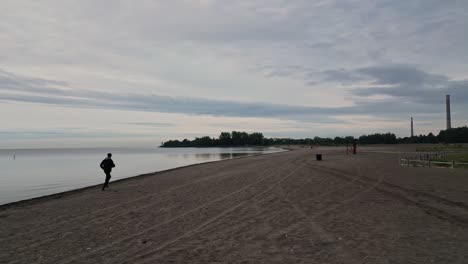 Hombre-Corriendo-En-La-Playa-De-Woodbine-En-Toronto,-Ontario-Al-Amanecer