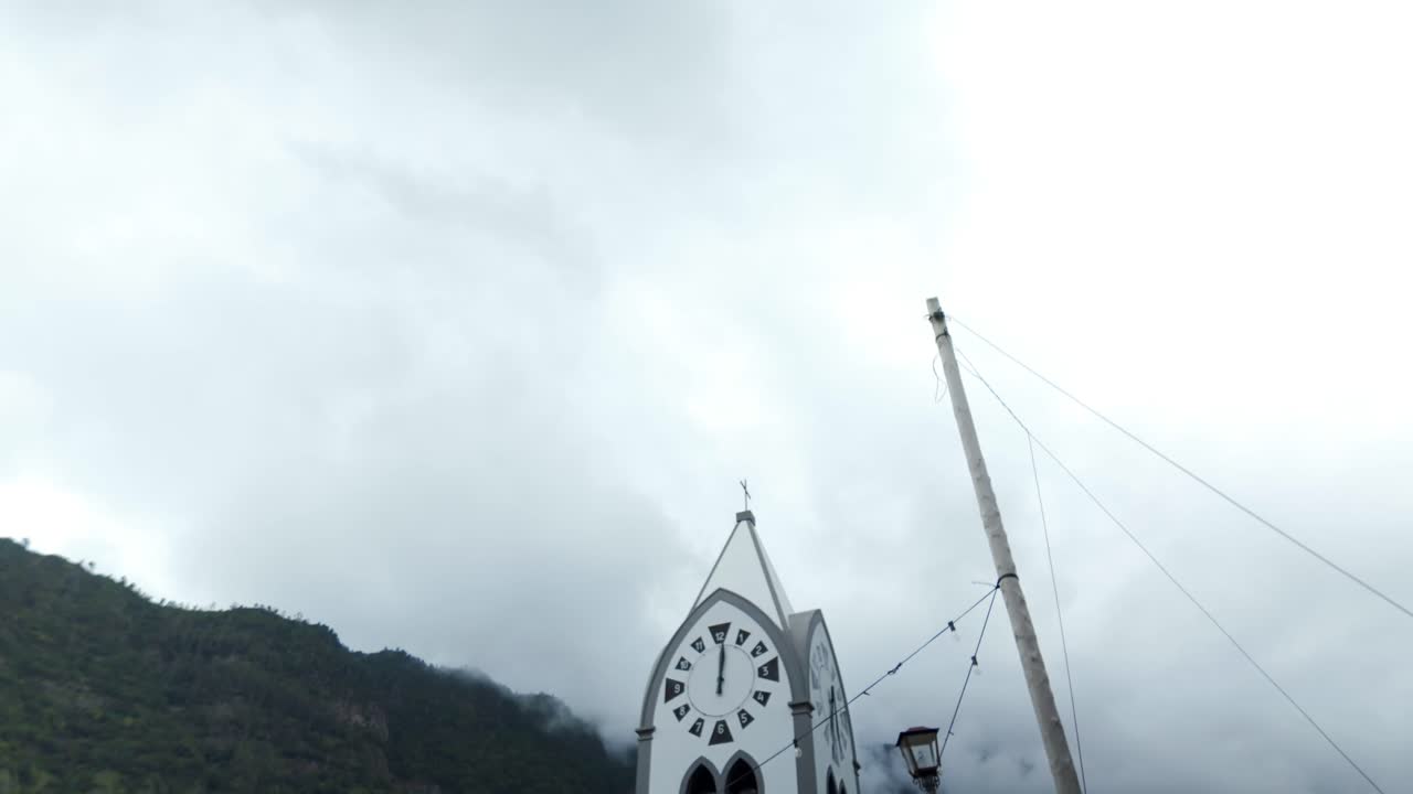 São Vicente, Madeira—tilt-down from church clock tower to footbridge and village path, misty mountains behind
