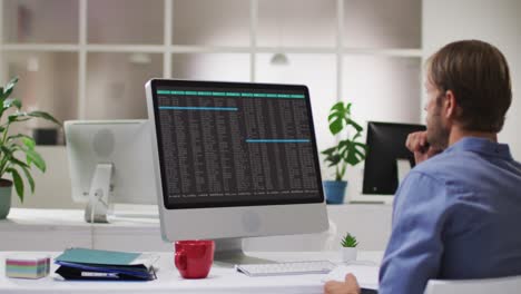 Caucasian man sitting at desk coding data on laptop