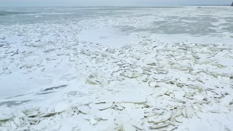 drone footage of ice shoves on lake that is freezing and thawing to create cracked iceburgs on surface