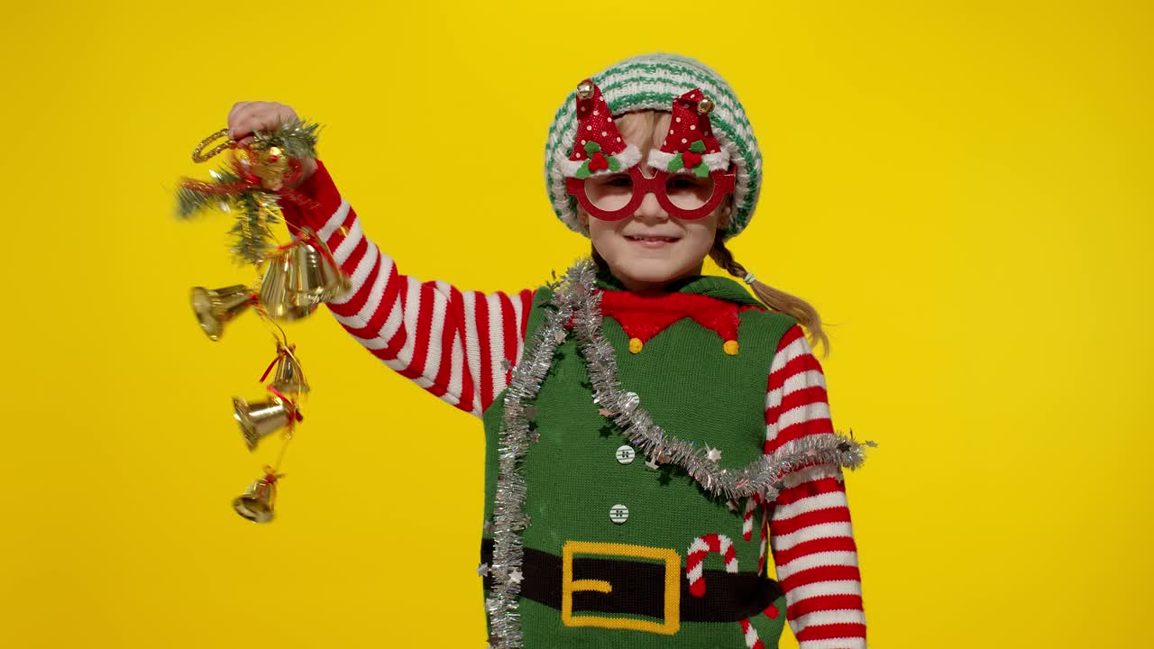 niña niña en navidad elf santa ayudante disfraz sosteniendo y sonando campanas juguete. vacaciones de año nuevo