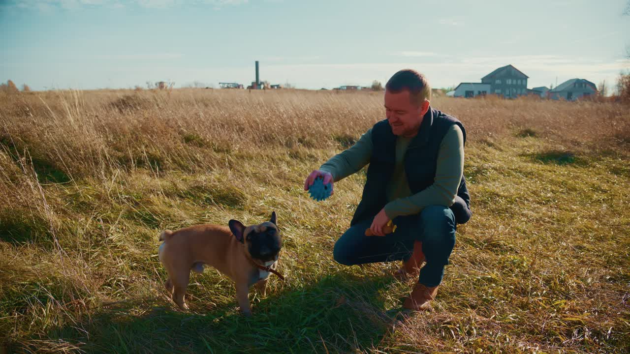 Un uomo si gode del tempo di qualità con il suo amato cane in un sereno campo aperto, ammirando la bellezza della natura durante una giornata di sole piena di momenti gioiosi e attività ludiche insieme