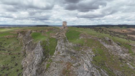 Aerial-drone-approaching-view-of-a-medieval-watch-tower-in-Burgo-de-Osma,-Soria,-Spain,-in-the-top-of-a-hill