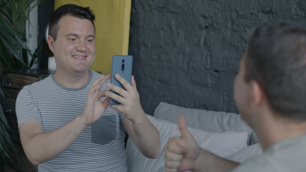 Due uomini che fanno una videochiamata o un selfie in camera da letto