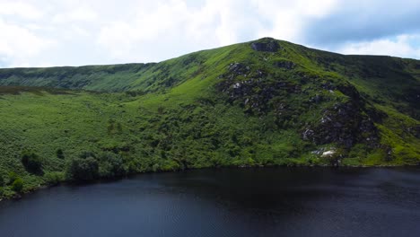 acercamiento descendente aéreo hacia un hermoso lago de montaña en irlanda