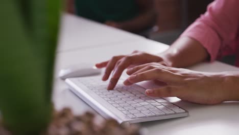 close up of mixed race businesswoman's hands typing on computer keyboard