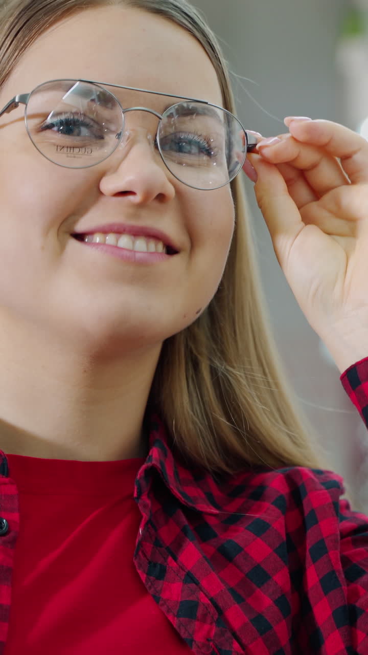 Donna che sceglie nuovi occhiali. Giovane donna felice che sceglie occhiali in un negozio di ottica.