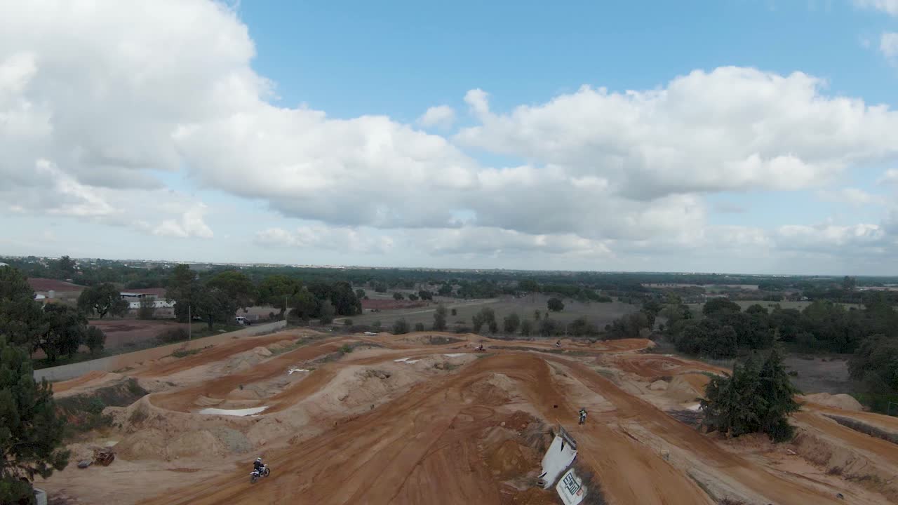 Descending aerial view of motocross riders jumping and riding on track