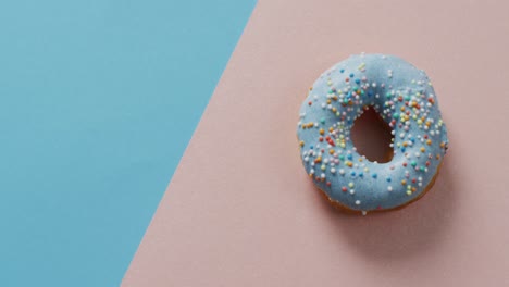 video of donut with icing on blue and pink background