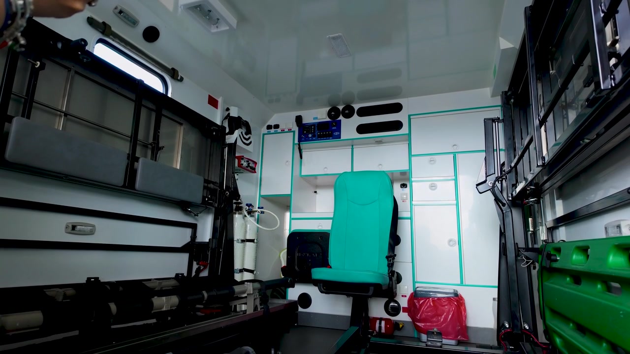 Un'inquadratura interna grandangolare di un'ambulanza pulita e moderna, dotata di vani per attrezzature mediche, bombole di ossigeno e sedili per paramedici. Adatta per temi legati alla sanità e ai servizi di emergenza