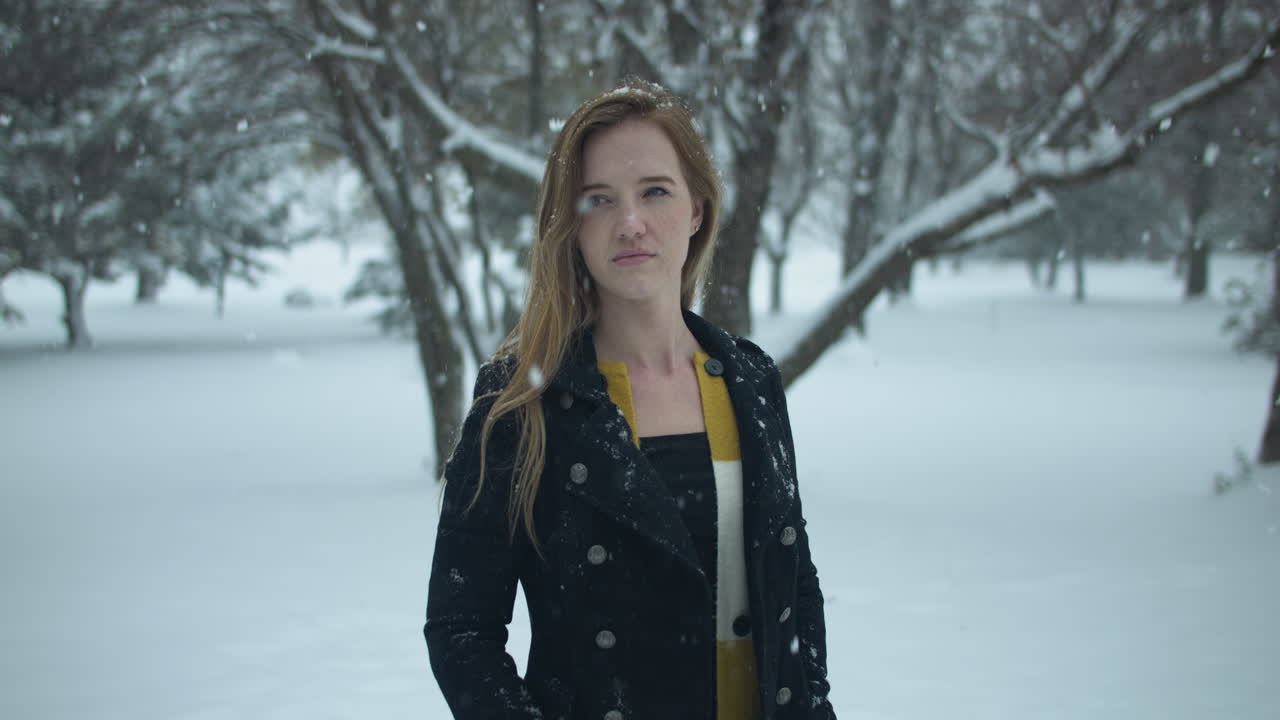 Glad kvinde udenfor i slowmotion vintersne, mens snefnug falder i filmisk slowmotion