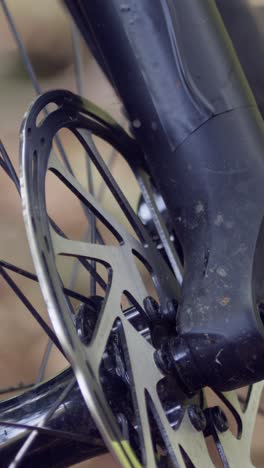 Close-Up-Vertical-Video-Of-Brake-Disc-On-Wheel-Of-Mountain-Bike-On-Woodland-Trail-