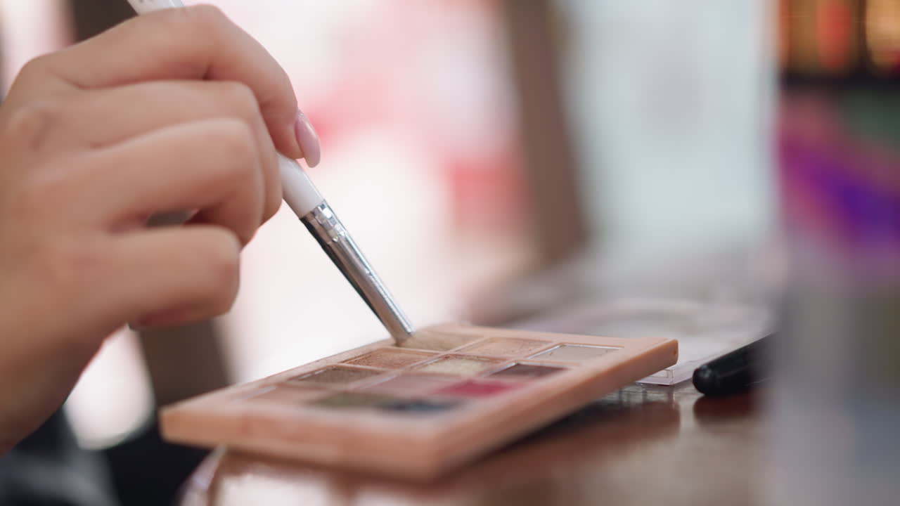 vista de primer plano de la mano de la dama sosteniendo un pincel de maquillaje mientras toca el polvo de contorno en el pincel desde la paleta de maquillajes, preparándolo para su aplicación en la cara, la belleza y el concepto de rutina de maquilaje