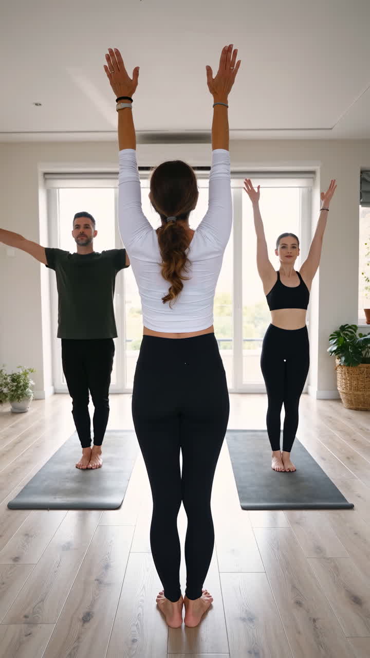 Tre persone che praticano yoga o stretching in una stanza luminosa.