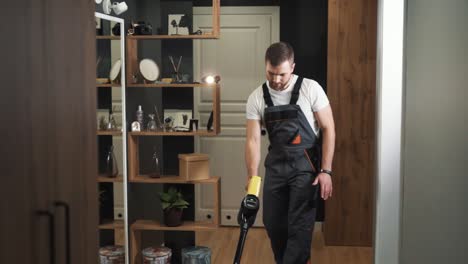 close-up of a man in a uniform cleaning with a cordless vacuum cleaner