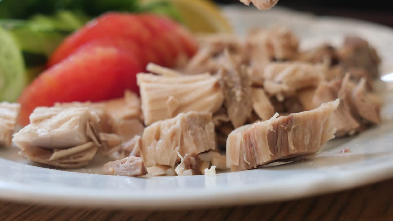 Primo piano di una forchetta che solleva un pezzo di pollo da un piatto con un contorno di insalata
