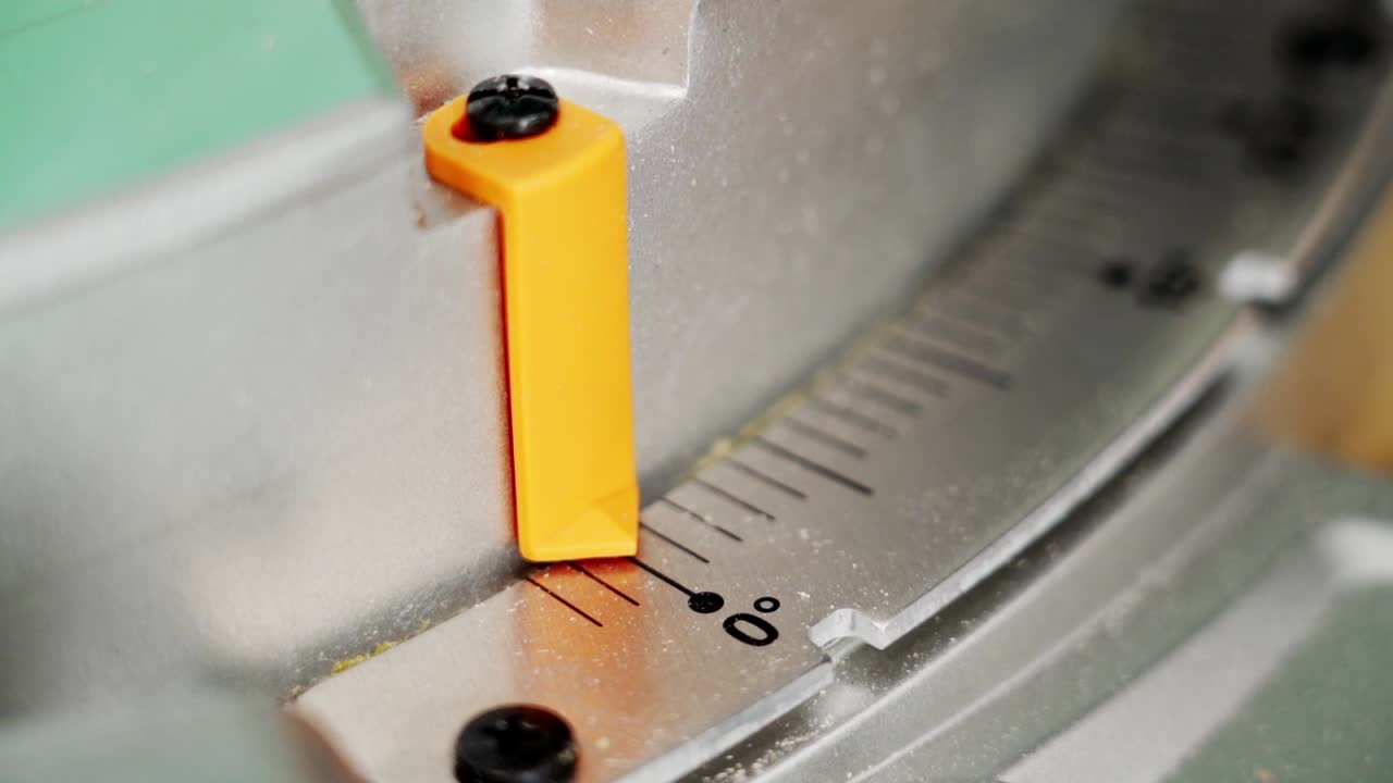 Close-up of a miter saw angle adjustment with an orange pointer