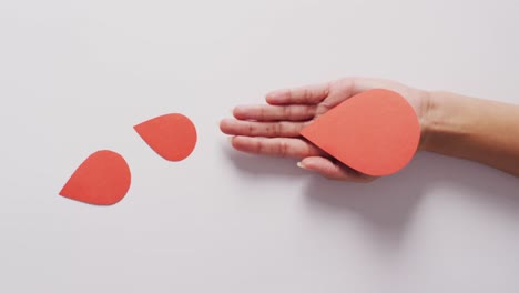 video of hands of caucasian woman holding paper blood on white background