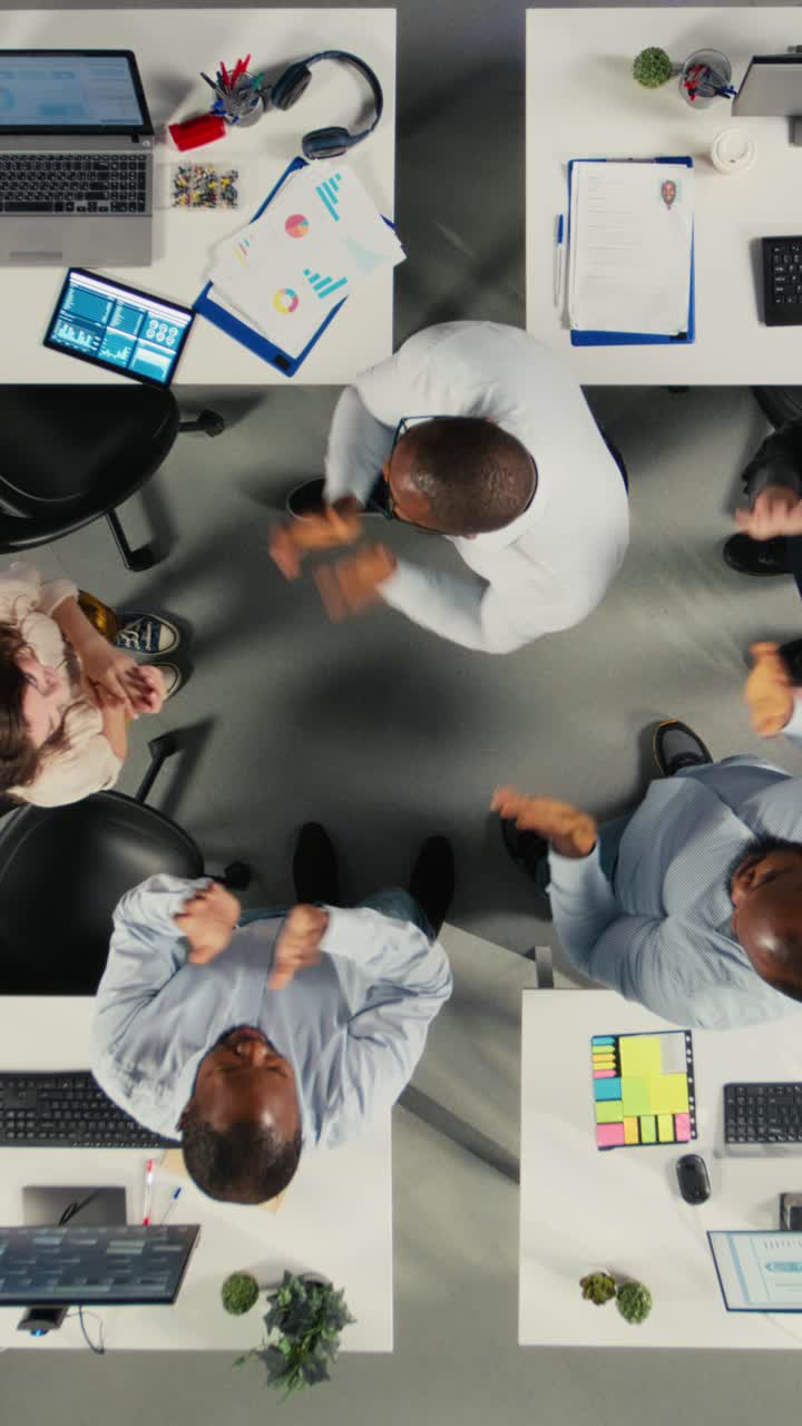 Vertical Video Top down view zoom out of company employees uniting hands and cheering
