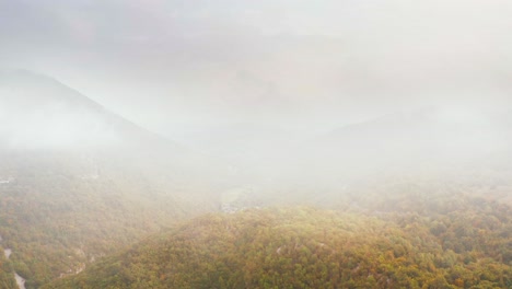 Epic-aerial-drone-shot-flying-over-colorful-mountainous-forest-in-autumn