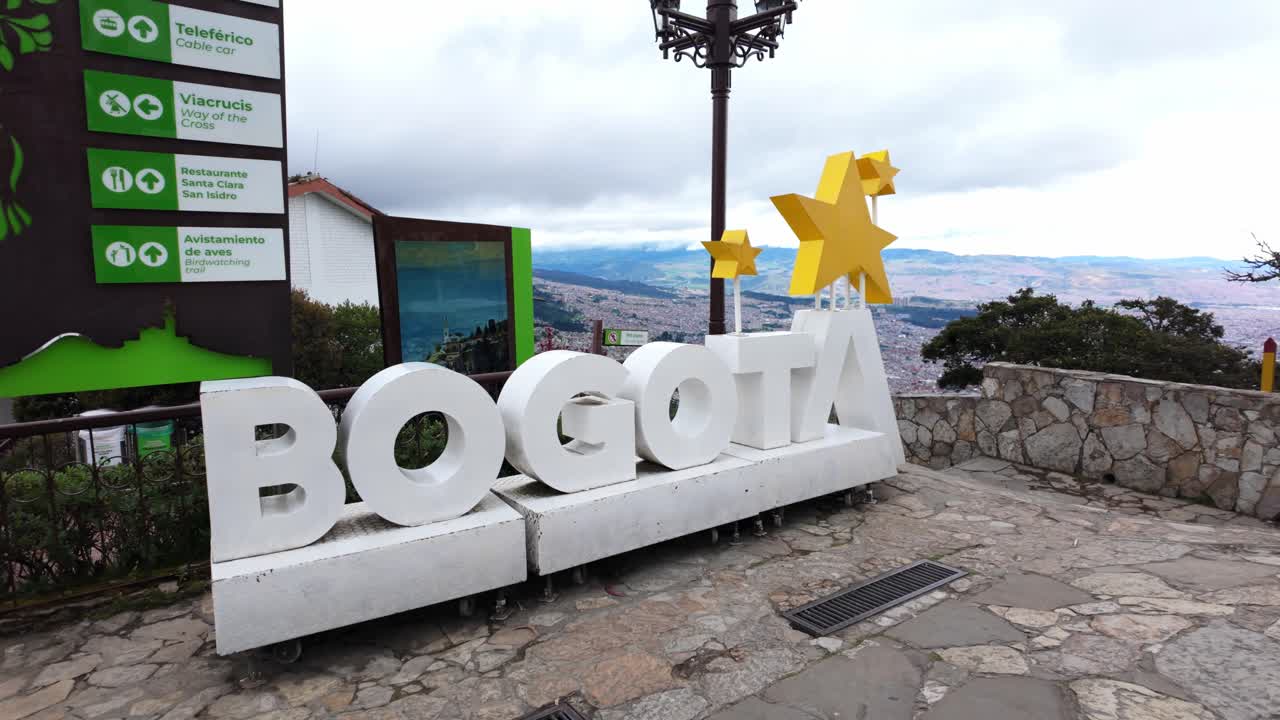 Large Bogotá sign at Monserrate viewpoint with scenic city views in the background, showcasing a popular tourist attraction in Bogotá, Colombia