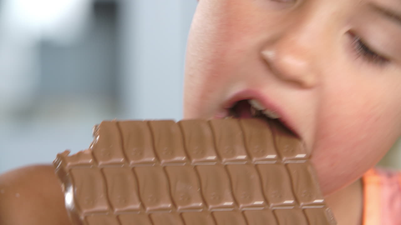 un primer plano de una chica comiendo una barra de chocolate.
