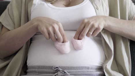 pregnant woman playing with babys bootees on belly