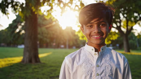 portrait of a smiling young boy in a sunny park
