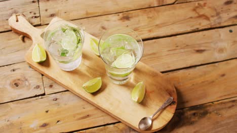 close up of drinks with lemons on wooden board, with copy space