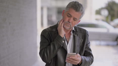 Thoughtful-mature-man-using-cell-phone-outdoor