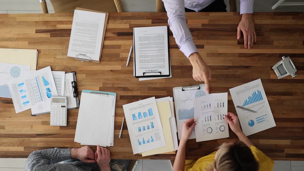 Business meeting with documents and charts on wooden table
