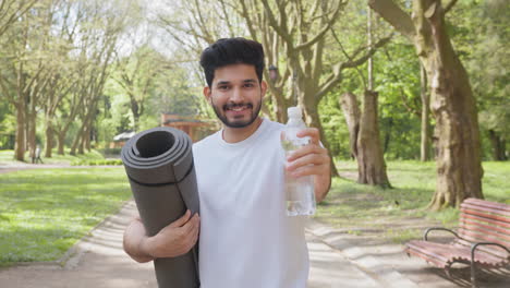 man in a park with yoga mat and water bottle