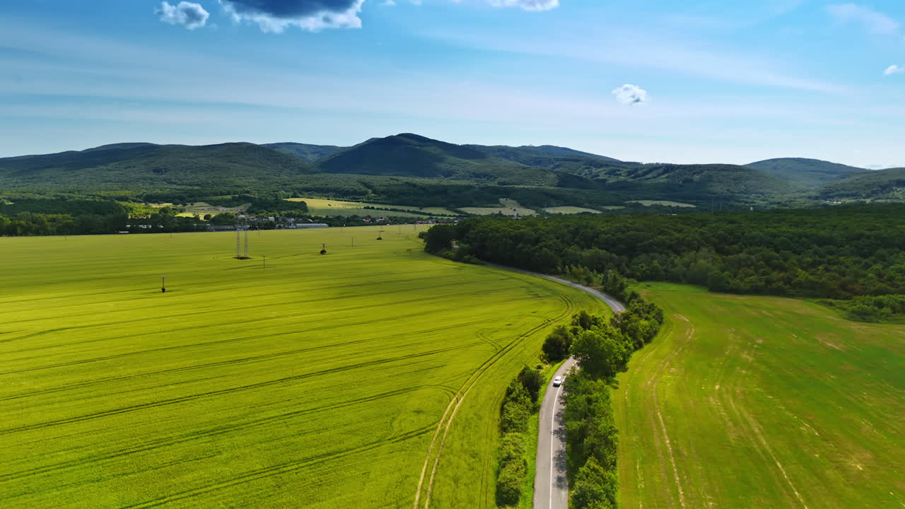 Green fields and hills in Europe. Vibrant green fields stretch across the landscape under a clear blue sky in a serene European countryside setting