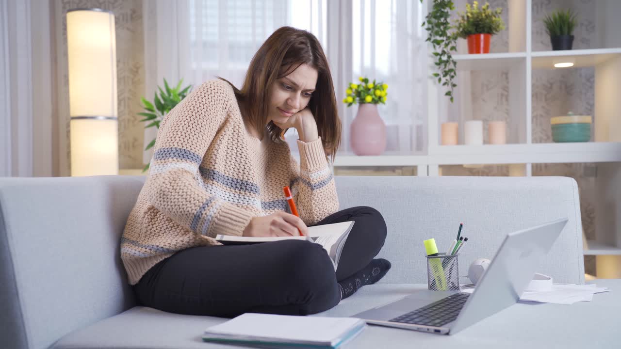 una joven universitaria descansando y estudiando en el sofá en casa.