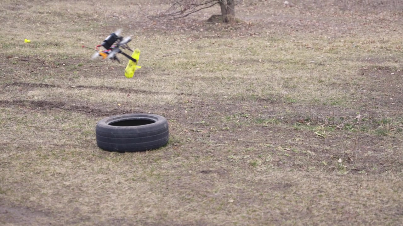Drone flying over open dirt field near tire obstacle demonstrating controlled movement outdoors