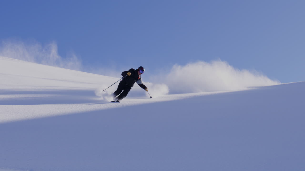 Freeride skier skinning up with Dents du Midi backdrop, then charging steep powder on a bluebird day near Champéry and Avoriaz.
