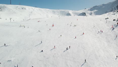 aerial drone shot flying toward a ski slope with numerous skiers descending in andorra.