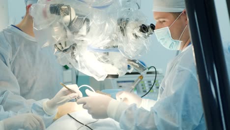 surgeons perform an operation and look through a microscope