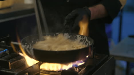 cocinero profesional que prepara fideos con salsa