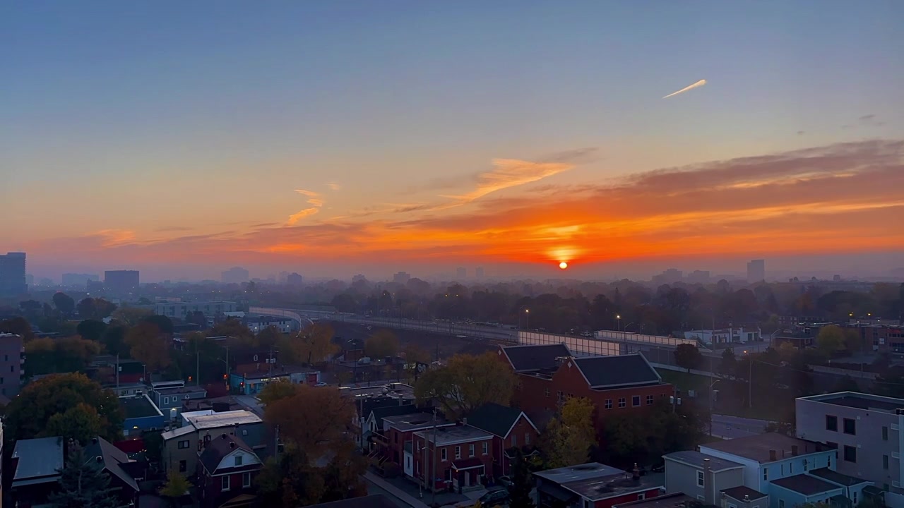 Time-lapse fra tidlig morgen, som viser solrik daggry, høstfarger, tett motorveitrafikk i Ottawa, nabolagshus og tynne skyer som beveger seg gjennom området, utvendig høyt vidvinkelbilde