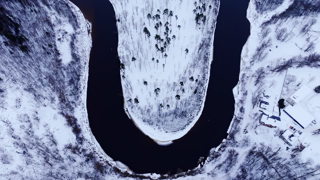 Cinematic top view of unfrozen Gauja River horseshoe bend in white snowy forest