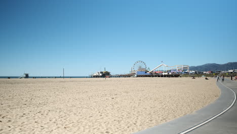 Parque-De-Atracciones-De-Carnaval-Distante-En-La-Playa-De-Arena-De-Santa-Monica-California,-En-Un-Día-Soleado