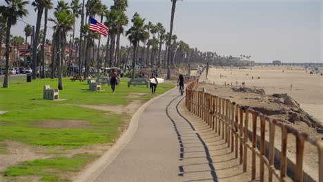 surfers walking along the bike path in huntington beach, california