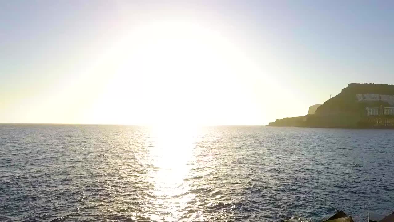 공중 비행기 소녀가 바다 뒤에서 해가 지는 것을 즐기고 있습니다.