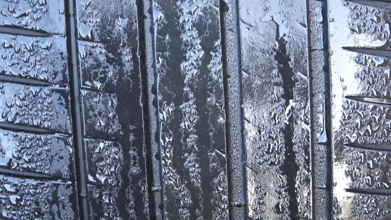 pneumatico per auto ad alta velocità bagnato con gocce di pioggia su di esso in vista ravvicinata.