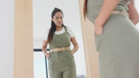 admiring herself in mirror, asian woman in green dress posing confidently, at home