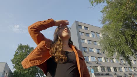 Low-angle-upward-to-woman-exploring-urban-city-hand-shading-eyes-held-high-at-attention