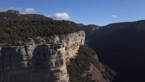 Aerial-of-steep-tree-covered-cliffs-with-panoramic-views,-zooming-shot