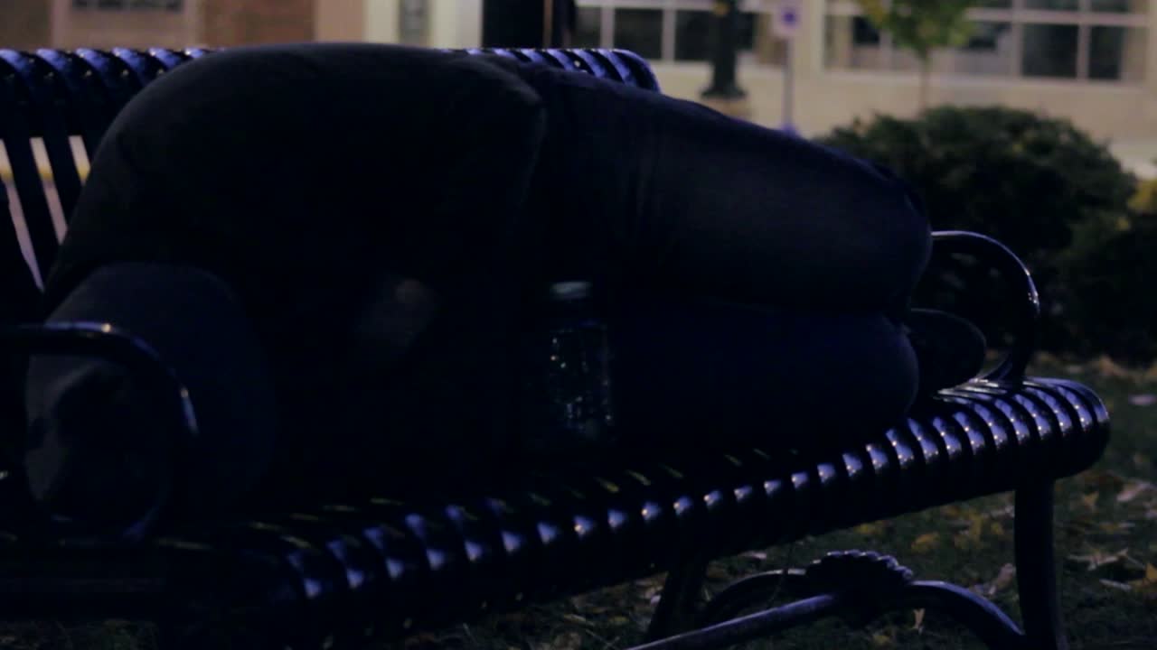 Homeless man sleeping on a park bench